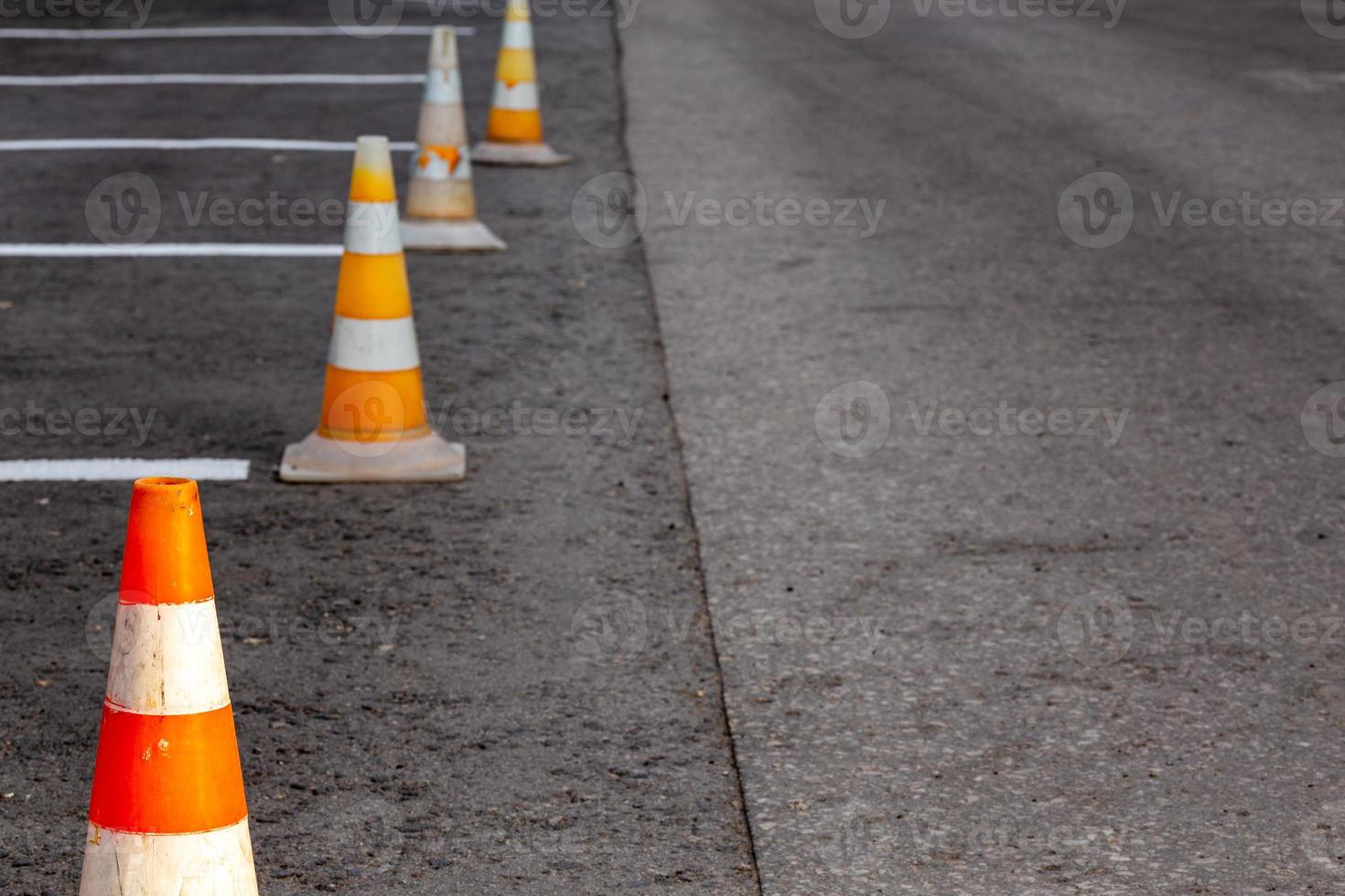 Orange road cones on a asphelt driving area with white lines photo