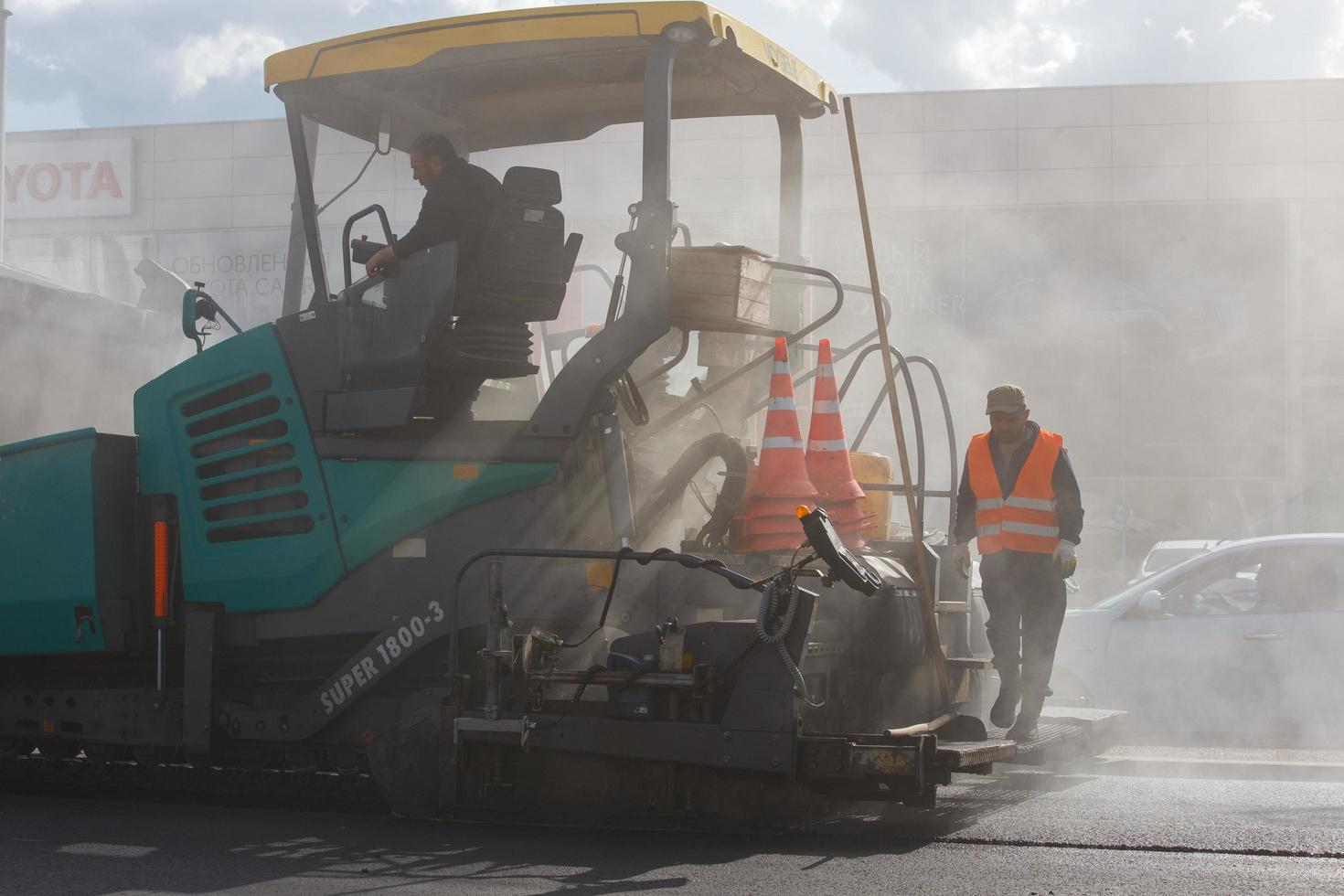 tula, rusia 16 de mayo de 2021 proceso de asfaltado, máquina pavimentadora de asfalto durante los trabajos de construcción de carreteras, en el día de verano foto