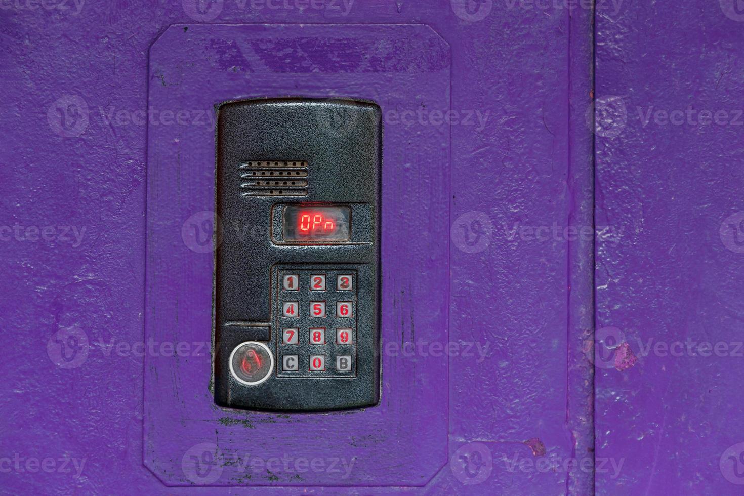 An intercom on purple painted red steel surface with a keypad, digital display and rfid sensor for calling close-up photo