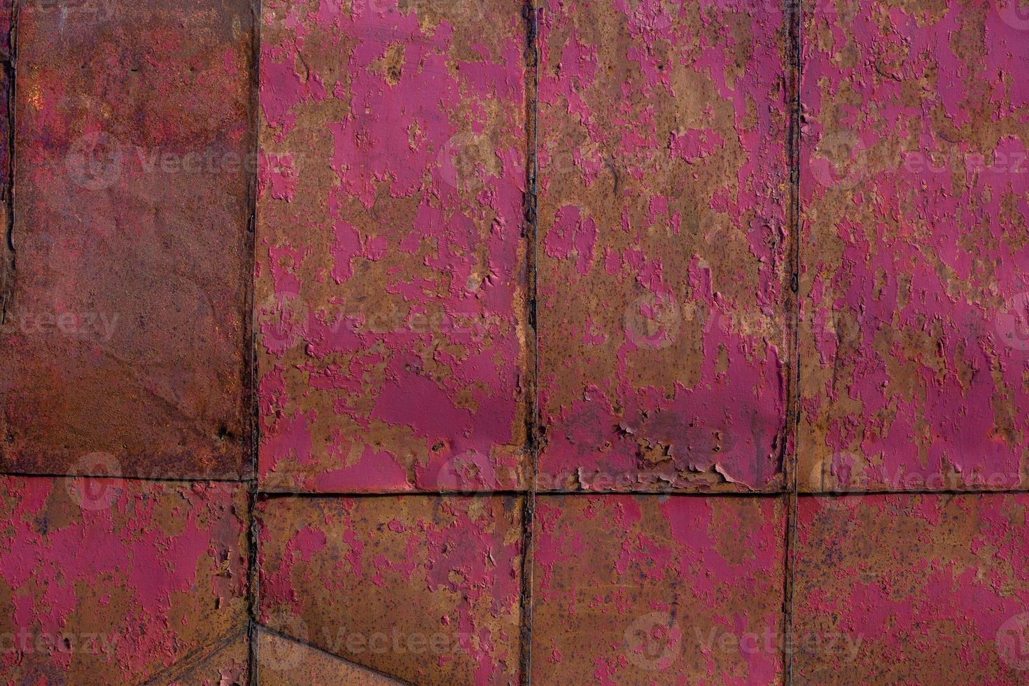 rusted tin sheets patchwork wall texture and flat background with peeling leftovers of pink paint photo