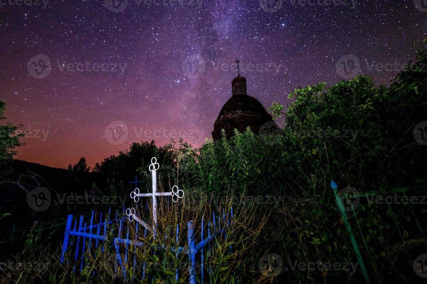 Abandoned christian grave under ruins of church at starry night with visible milky way galaxy. photo