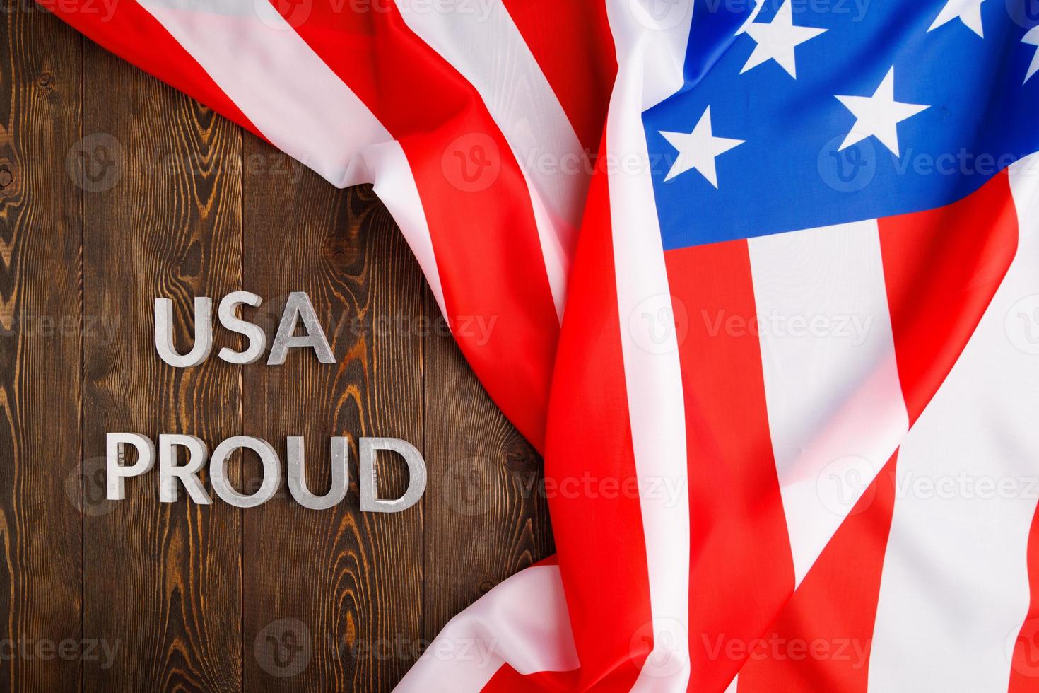 words USA proud laid with silver letters on brown wooden surface with US flag photo