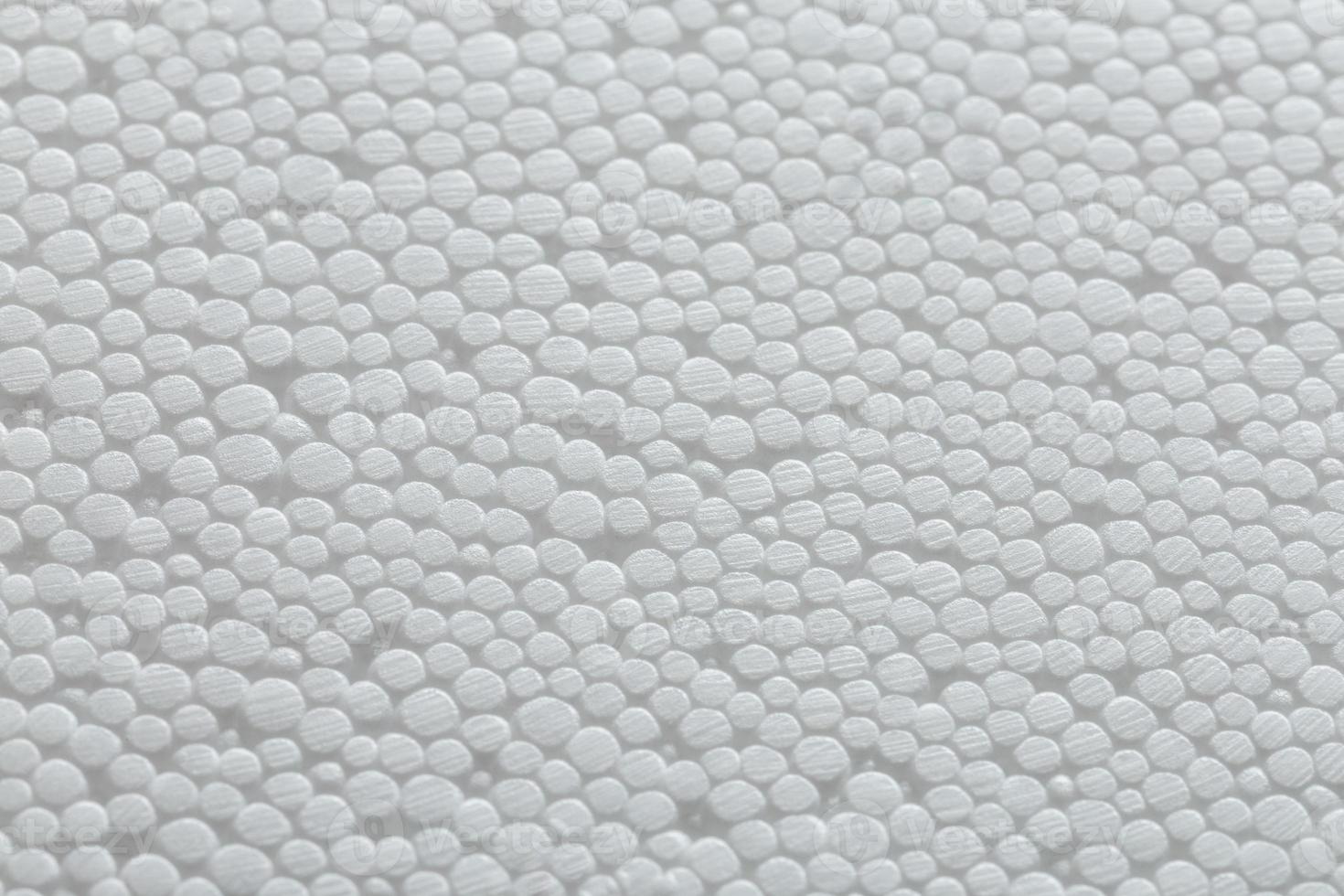 Simple close-up flat but bumpy background of white polystyrene foam or styrofoam, white on white backdrop with selective focus and partial blur. photo