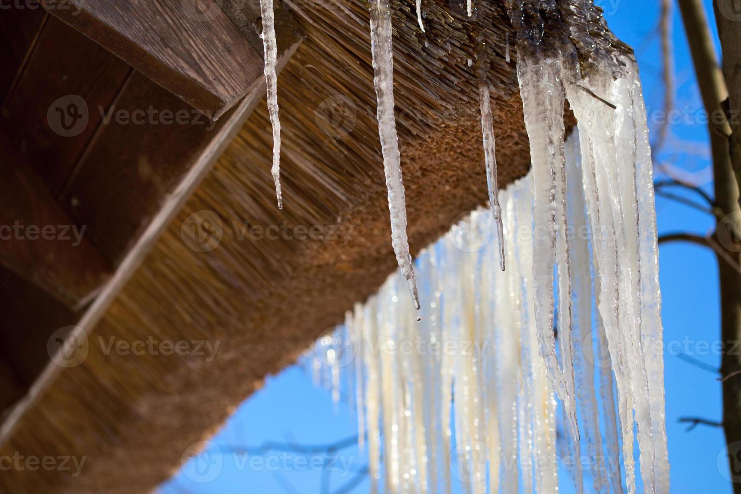 Icicles on wooden roof corner of house photo