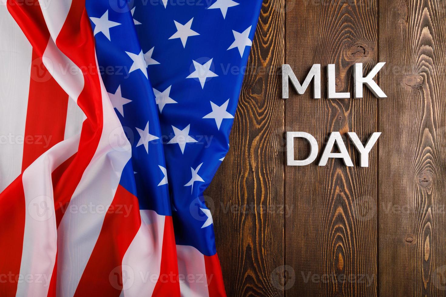 the word MLK day laid with silver metal letters on wooden surface with crumpled USA flag at left side photo