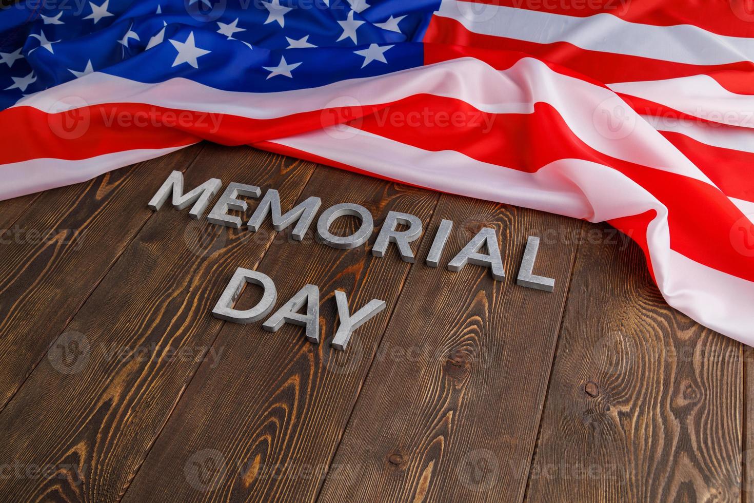 the words memorial day laid with silver metal letters on wooden board surface with crumpled usa flag photo