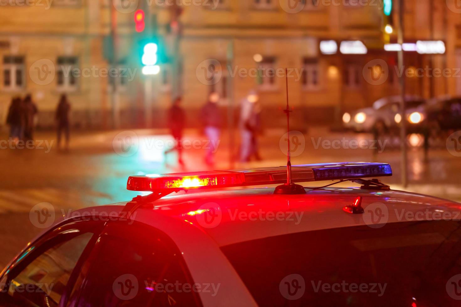 night police car lights in city street with blurry pedestrians crossing road in the background photo