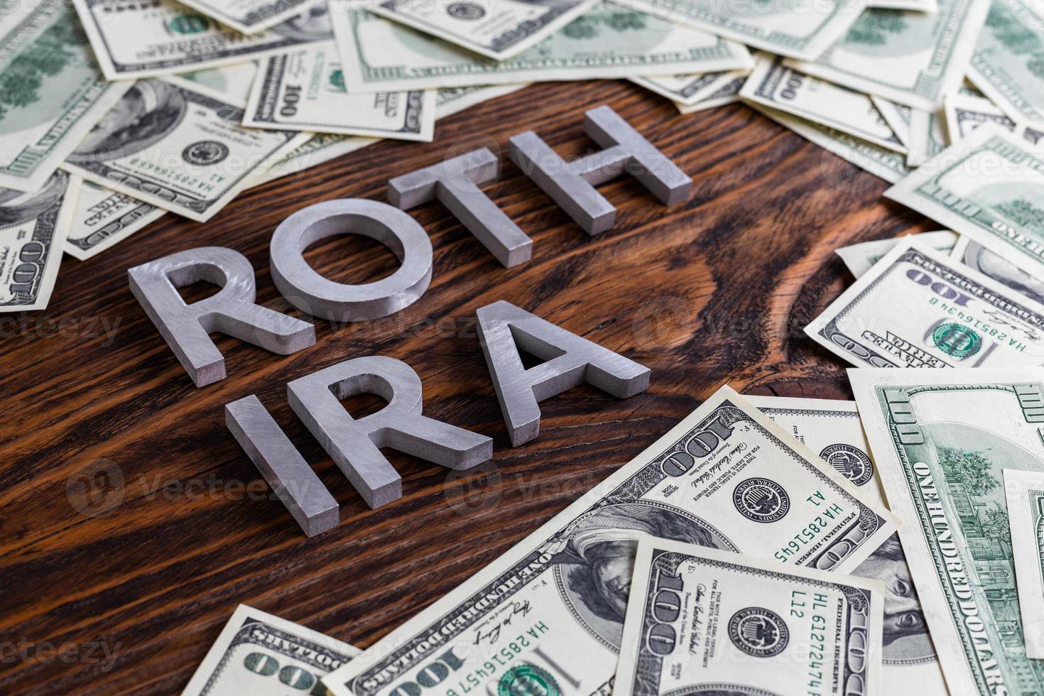 words ROTH IRA laid on wooden surface by metal letters with us dollar banknotes photo