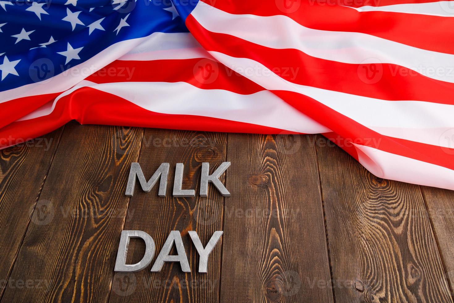 the word MLK day laid with silver metal letters on wooden surface with crumpled USA flag at upper side photo