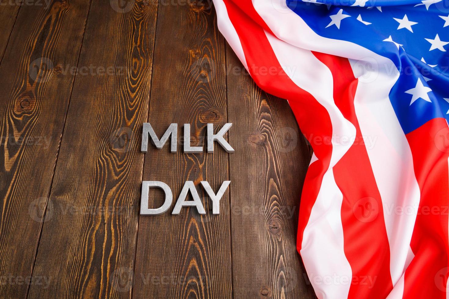 la palabra mlk day colocada con letras de metal plateado sobre una superficie de madera con una bandera de estados unidos arrugada en la parte superior foto