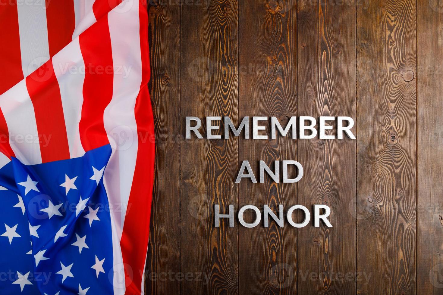 words remember and honor laid with silver metal letters on wooden background with USA flag on the left side photo