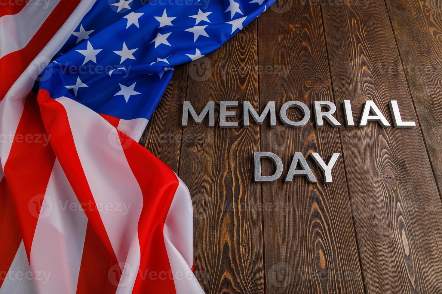 the words memorial day laid with silver metal letters on wooden board surface with crumpled usa flag photo