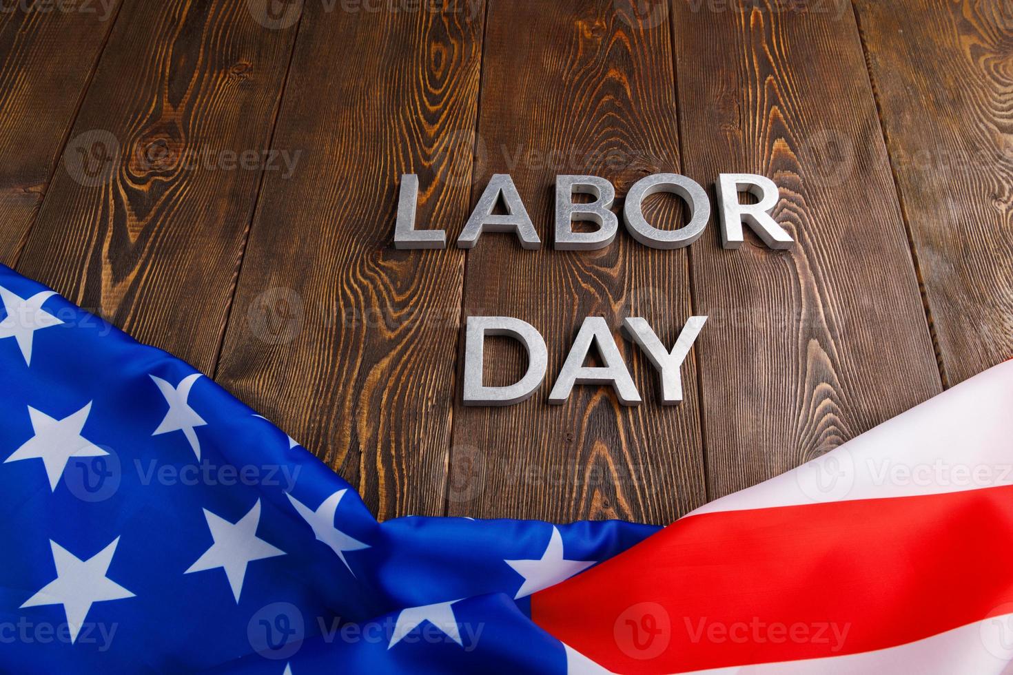 words labor day laid with silver metal letters on wooden surface with crumpled USA flag on bottom side photo