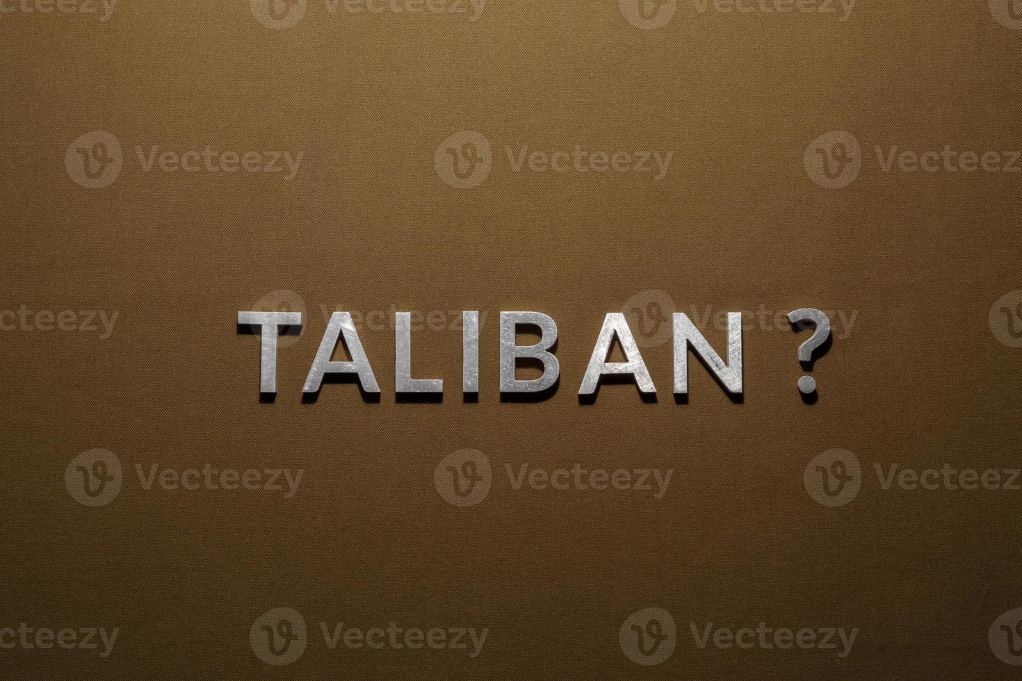 the question taliban laid with silver metal letters on rough tan khaki canvas fabric photo