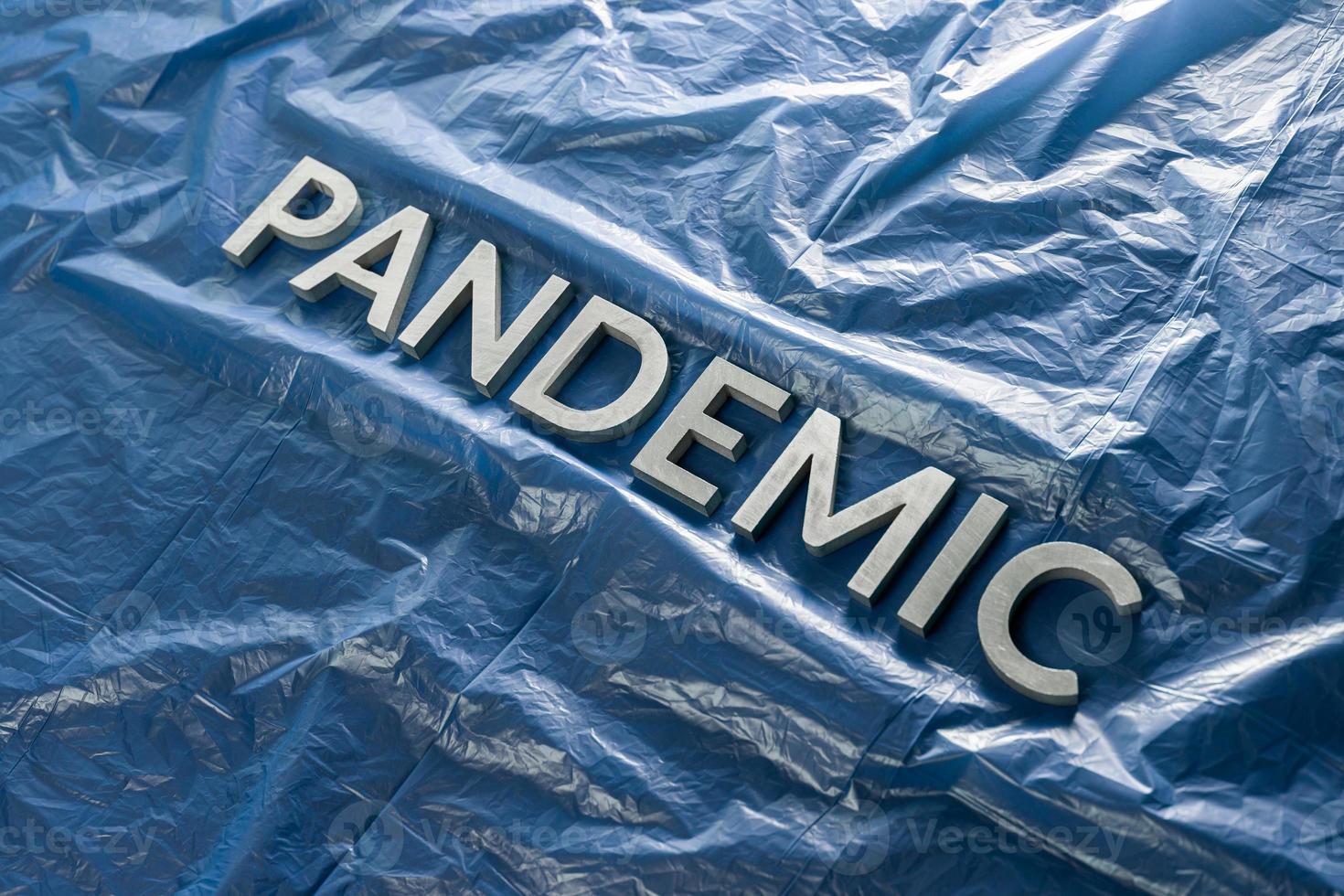 the word pandemic laid with silver letters on crumpled blue plastic film - diagonal perspective composition with selective focus photo