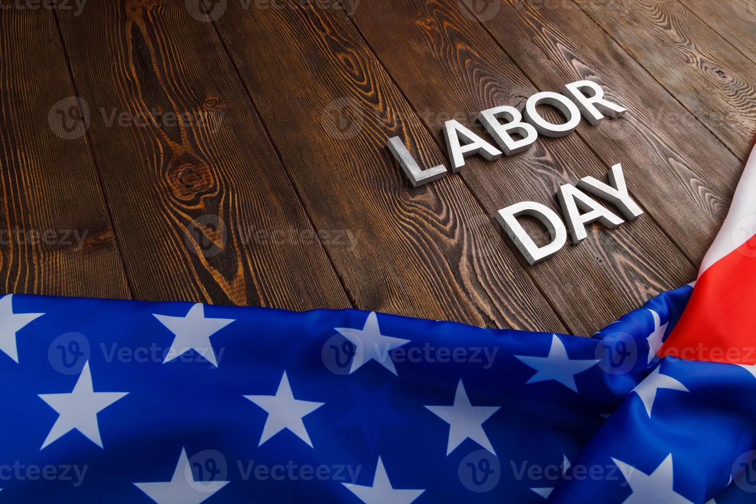 words labor day laid with silver metal letters on wooden surface with crumpled USA flag on bottom side photo