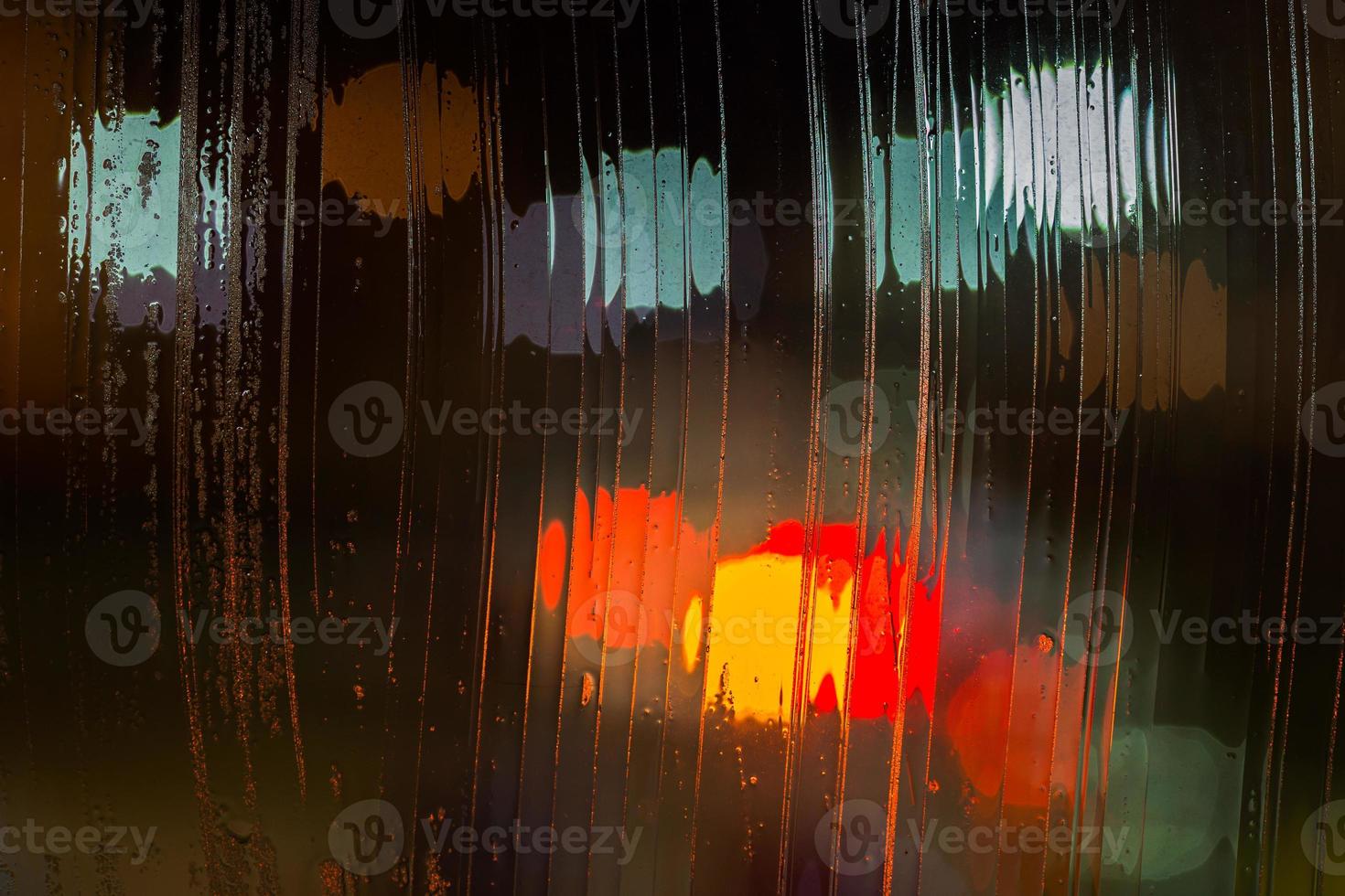 an abstract background night street lights bokeh through wet glass, close-up with selective focus photo