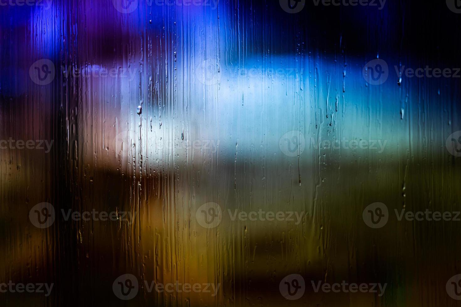 un fondo abstracto luces de la calle de noche bokeh a través de vidrio húmedo con gotas de agua, primer plano con enfoque selectivo foto