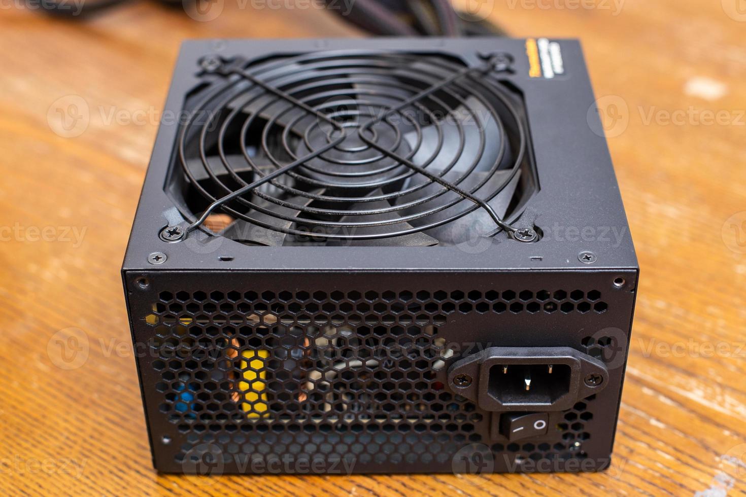 black ATX PC power supply unit on wooden surface photo