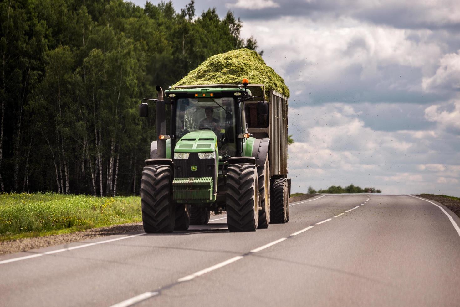 tula, rusia 30 de julio de 2019 tractor con ensilado verde en el remolque rodando por la carretera de verano foto