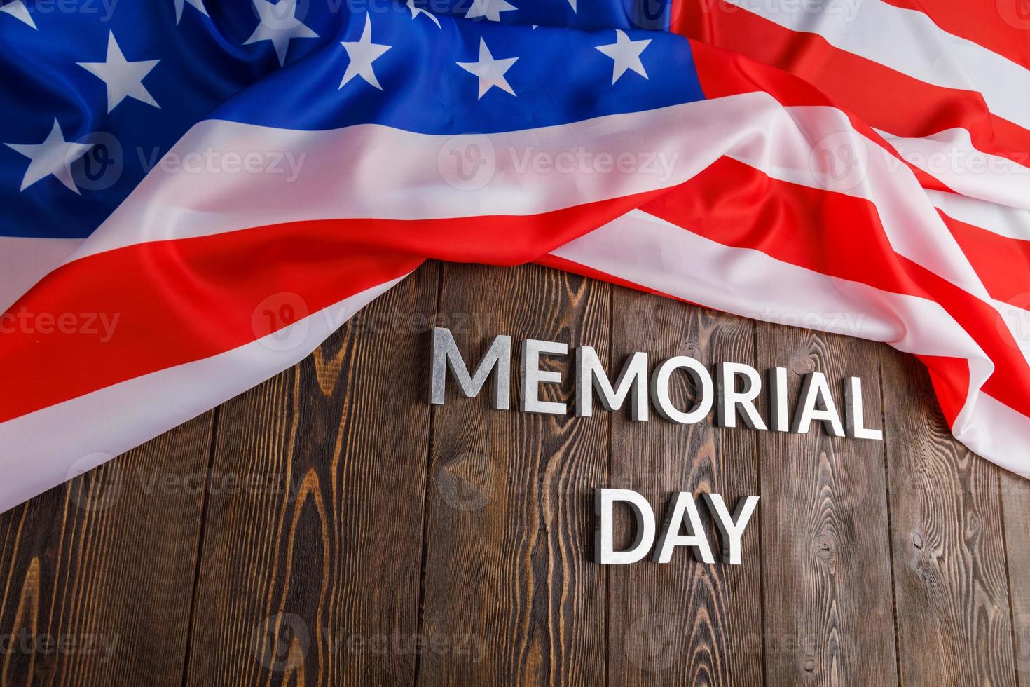 the words memorial day laid with silver metal letters on wooden board surface with crumpled usa flag photo