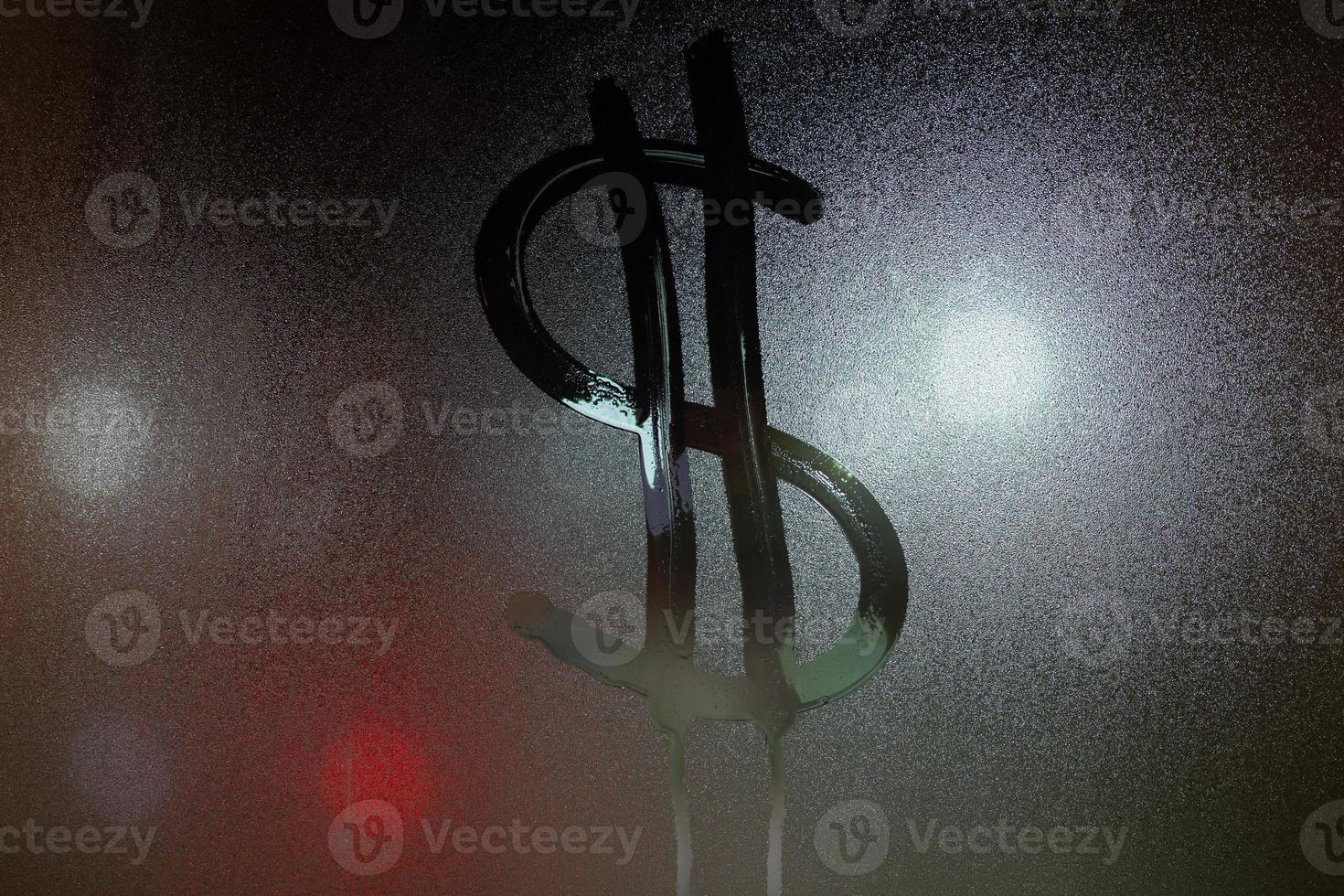 a dollar sign written on night wet window glass close-up photo