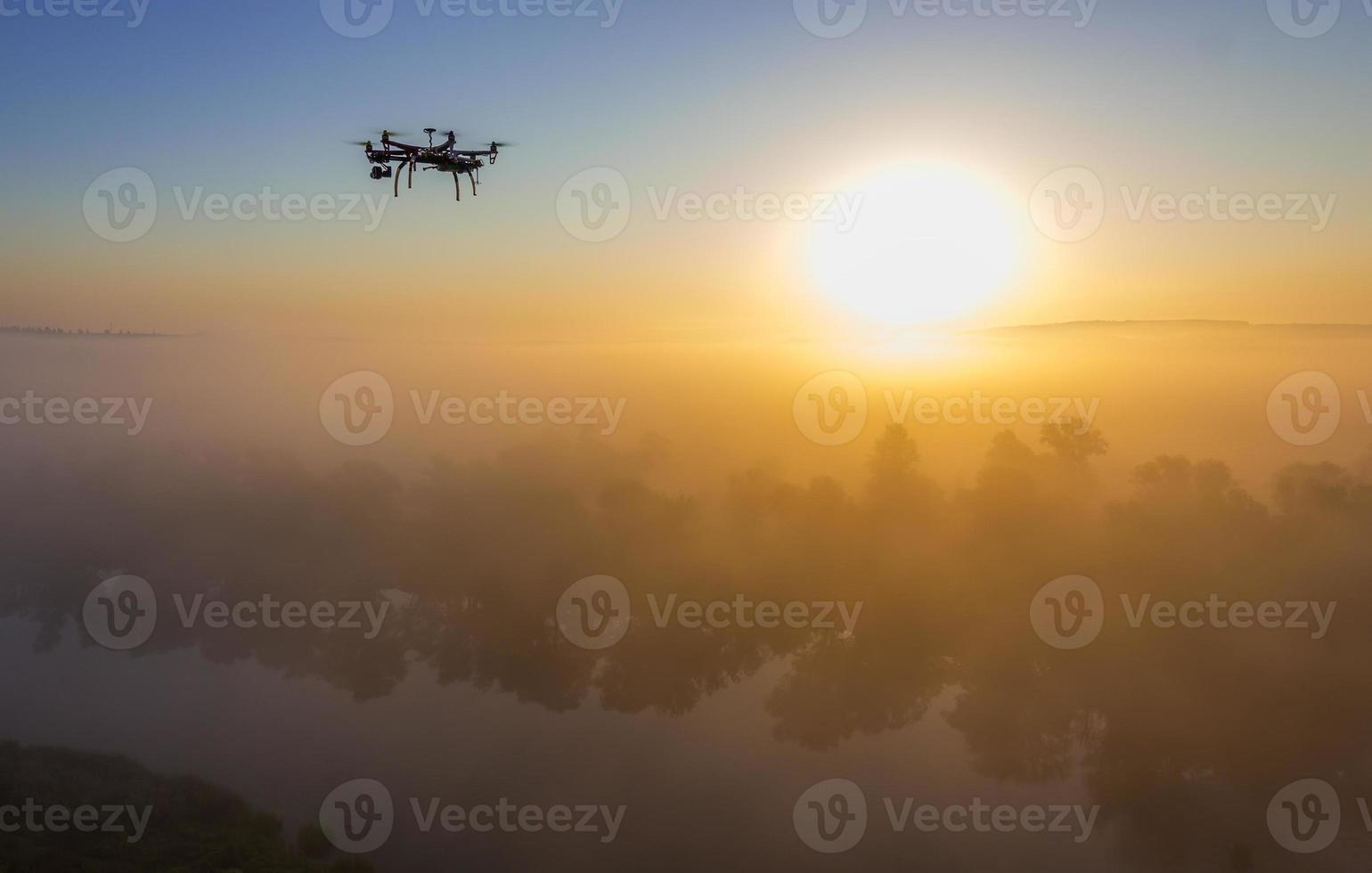 Hexacopter drone over foggy sunrise on river photo