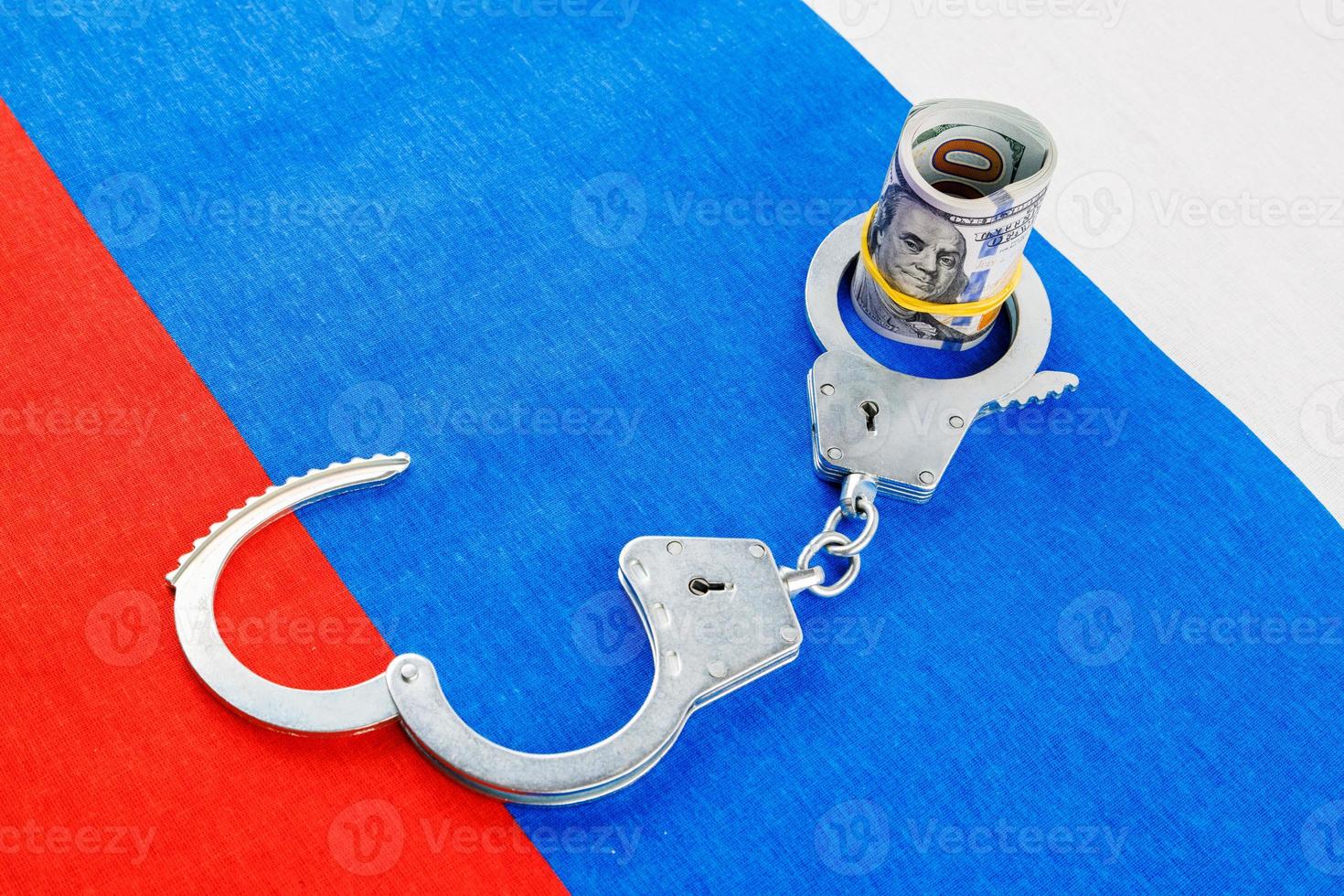 roll of us dollar banknotes in a handcuffs on flat full-frame russian flag photo