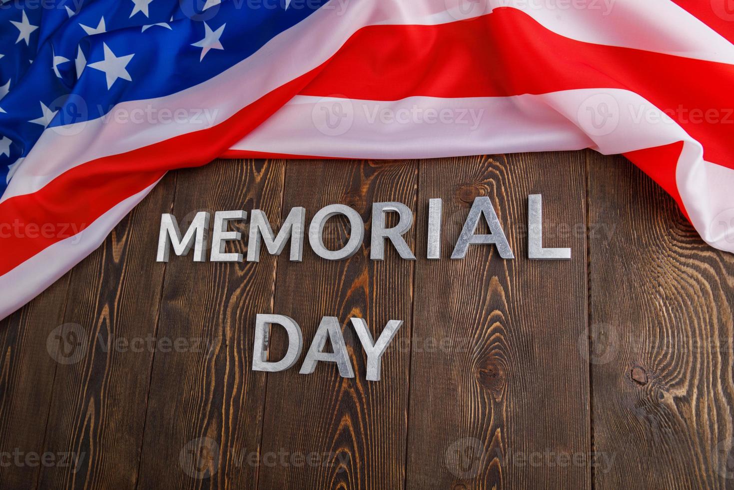 the words memorial day laid with silver metal letters on wooden board surface with crumpled usa flag photo