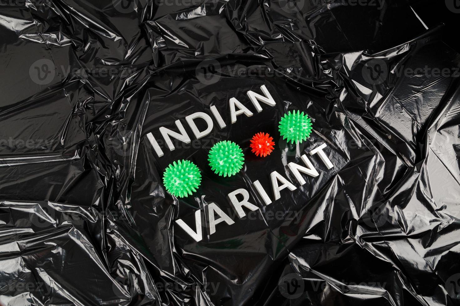 palabras variante india colocadas con letras de metal plateado sobre fondo de bolsa de plástico negro arrugado con pequeños modelos de virus foto