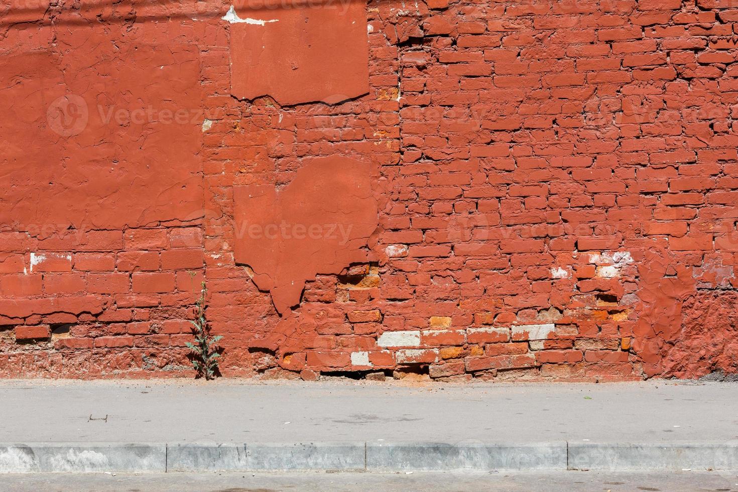 old brick wall with peeled off plaster, all over painted orange photo