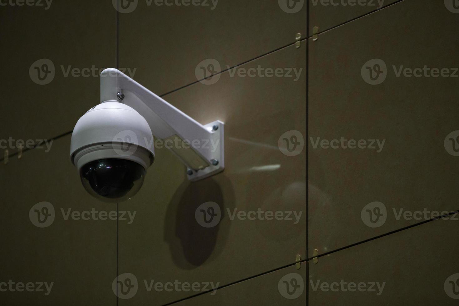 360 degree ball surveillance security camera on building wall at night photo