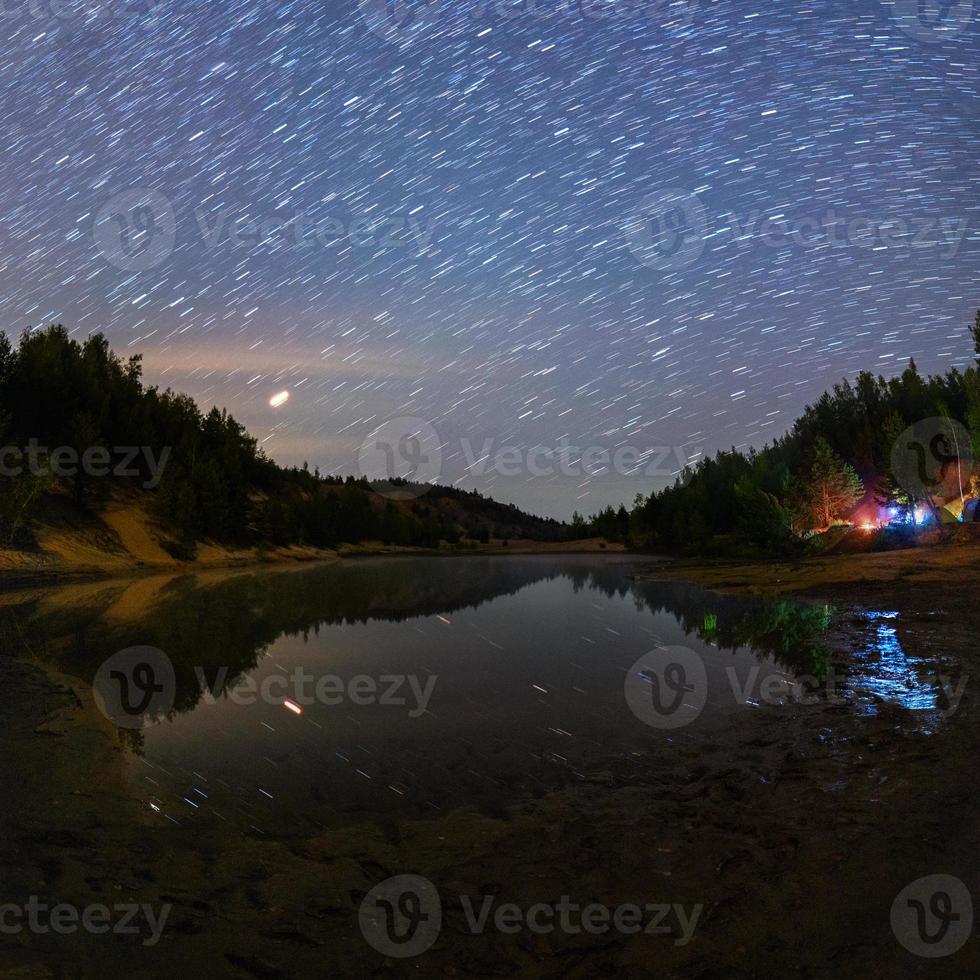 small lake under stars at night with short rails and camping at summer photo