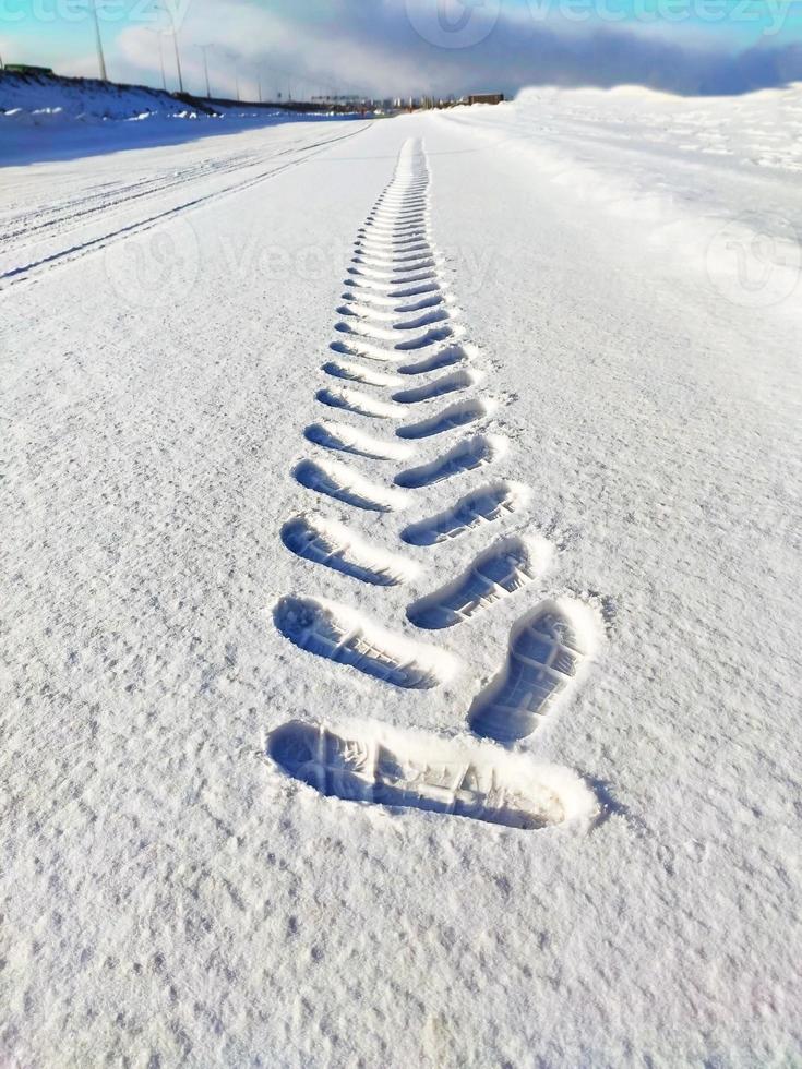 pattern of a footprint from a shoe in the snow extending into the distance photo