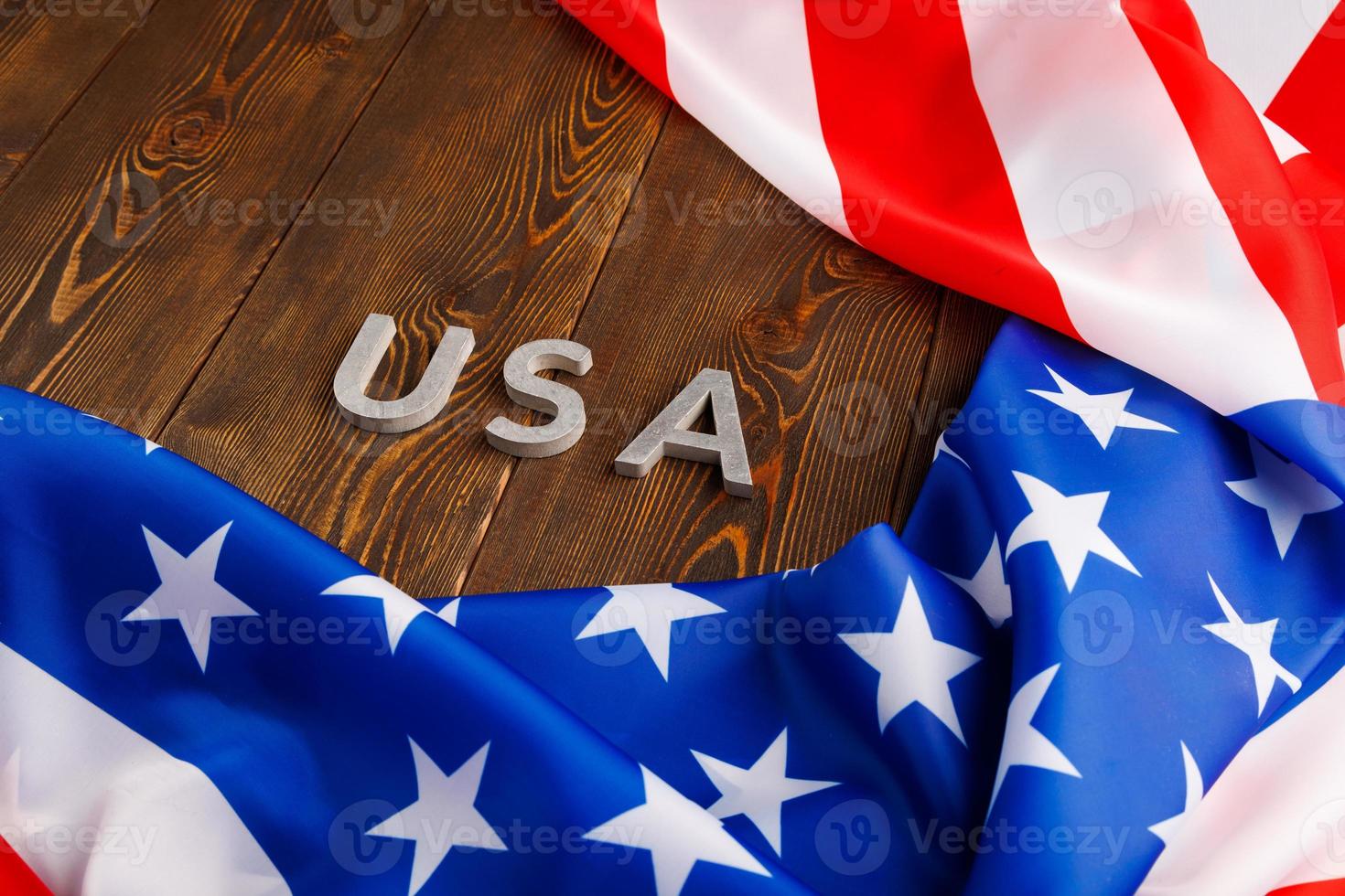 la palabra ee.uu. colocada con letras de metal plateado en la superficie de una tabla de madera bajo la bandera arrugada de los estados unidos de américa foto