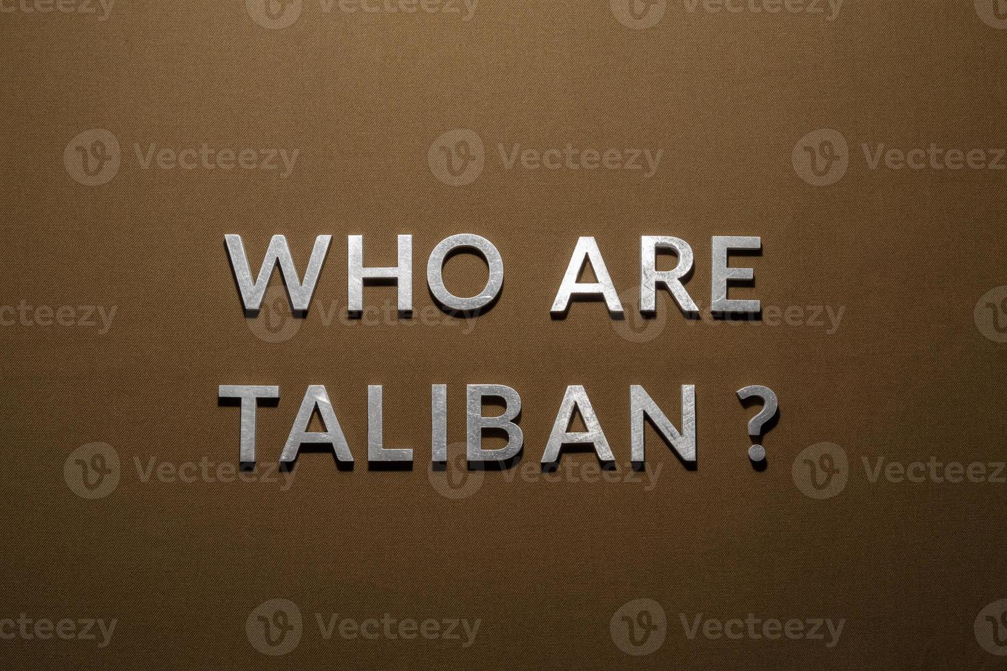 the question who are taliban laid with silver metal letters on rough tan khaki canvas fabric photo