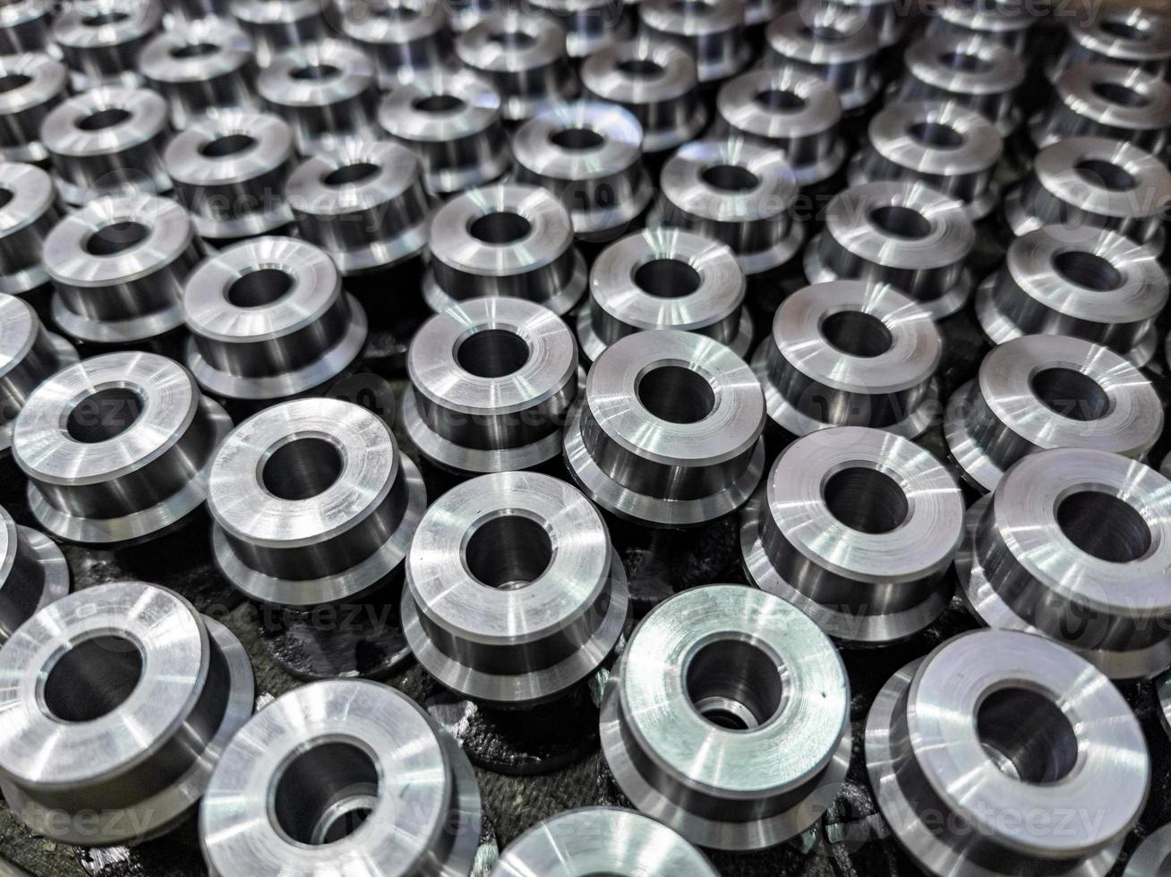 batch of shiny round steel parts background, close-up with selective focus and blur photo