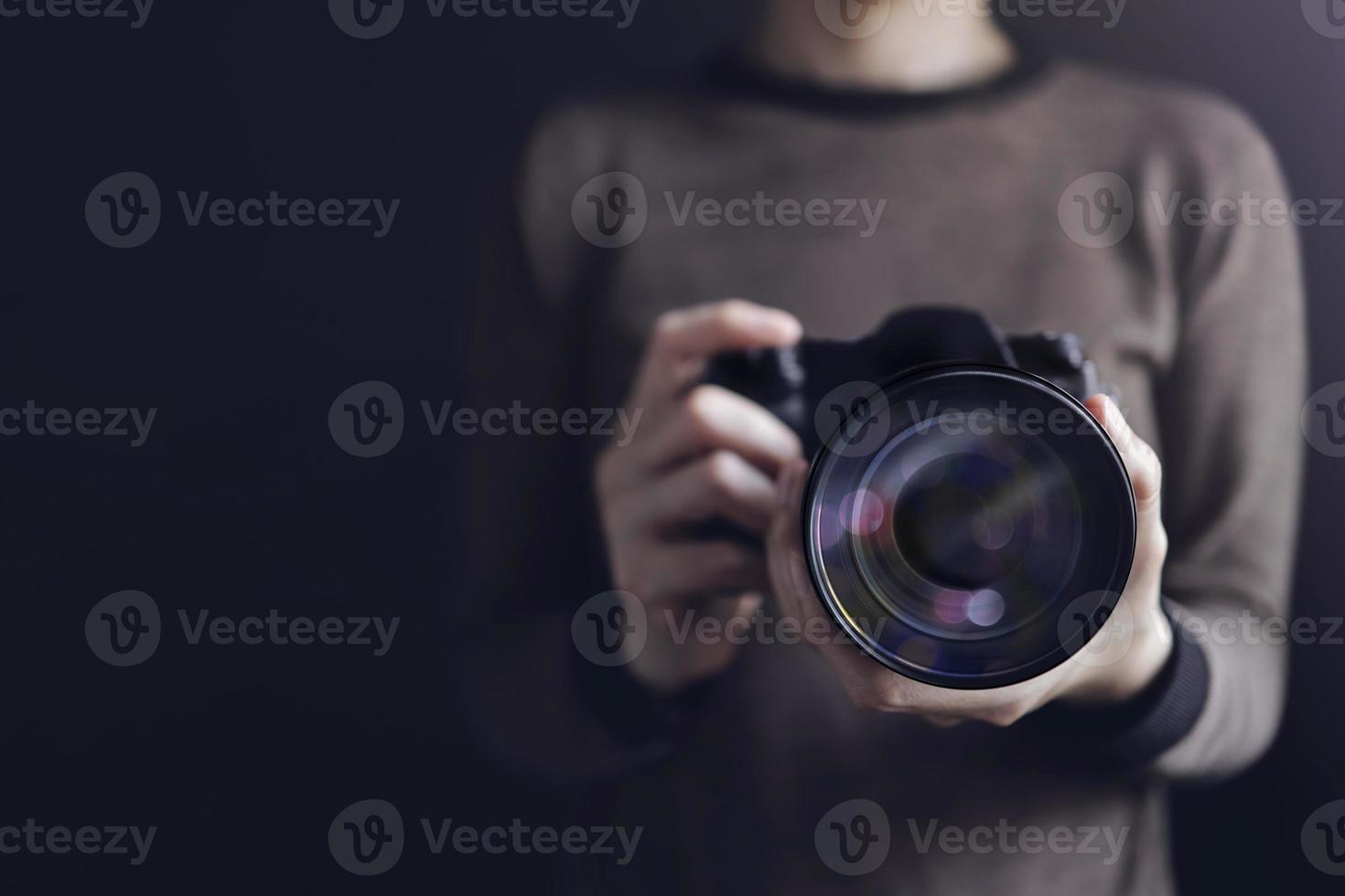 Photographer Taking Self-Portrait. Woman using Camera to Taking Photo. Dark Tone, Front View. Selective focus on Lense. Straight into a Camera photo