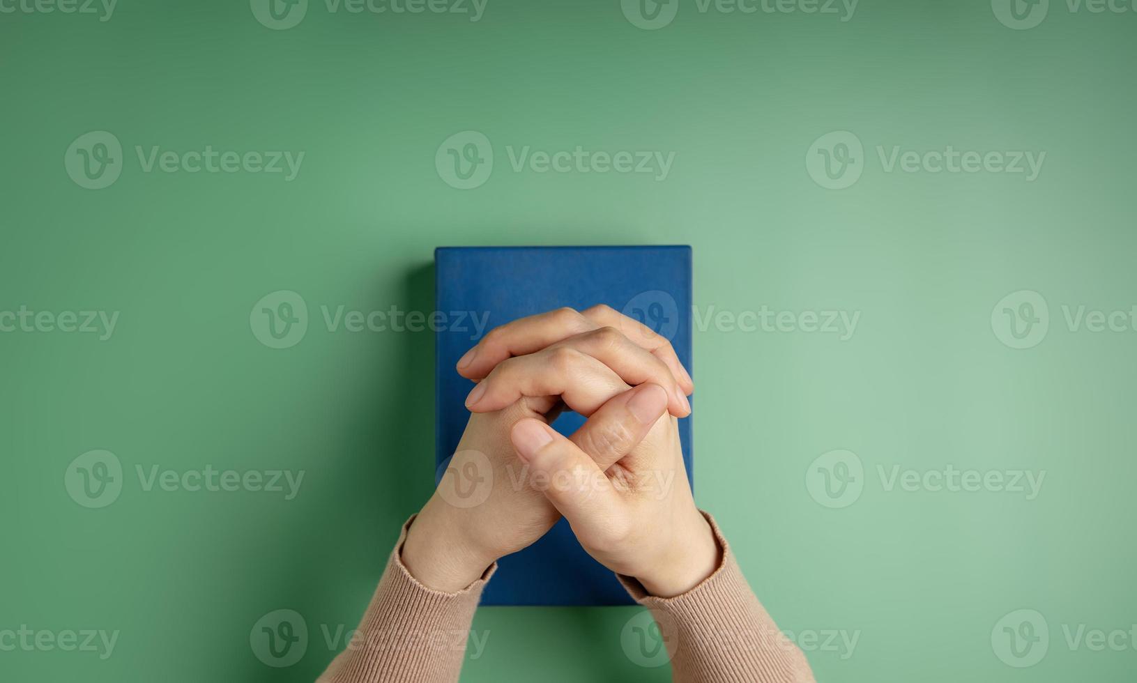 Spirituality, Religion and Hope Concept. Person Praying by Holy Bible on Desk. Symbol of Humility, Supplication,Believe and Faith for Christian People. Top View photo