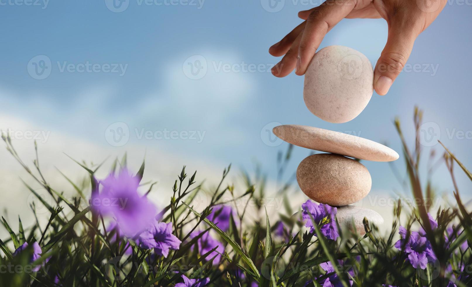 Enjoying Life Concept. Harmony and Positive Mind. Hand Setting Natural Pebble Stone with Smiling Face Cartoon to Balance Flower Garden. Balancing Body, Mind, Soul and Spirit. Mental Health Practice photo