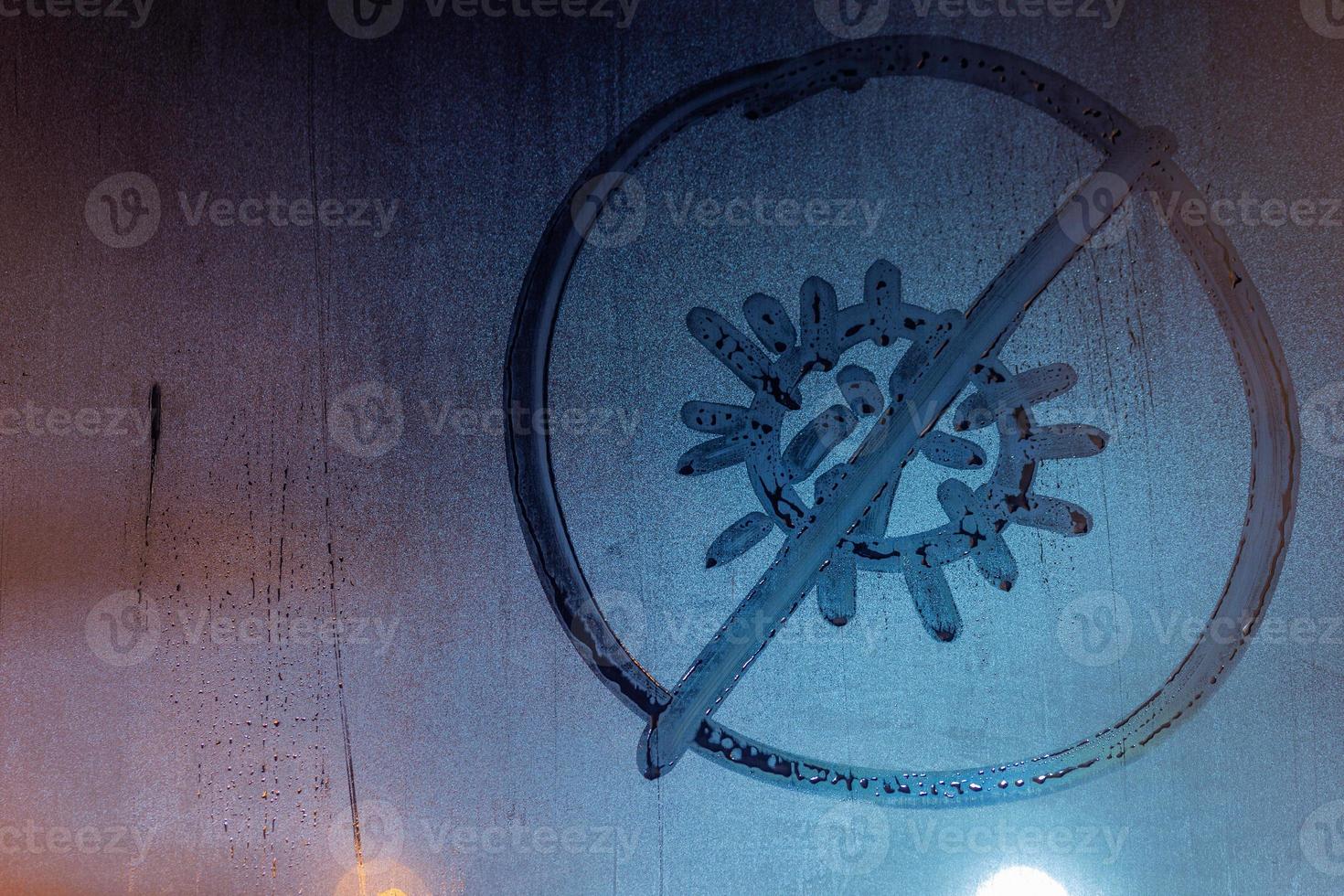 banned coronavirus icon handwritten on night wet window glass close-up photo