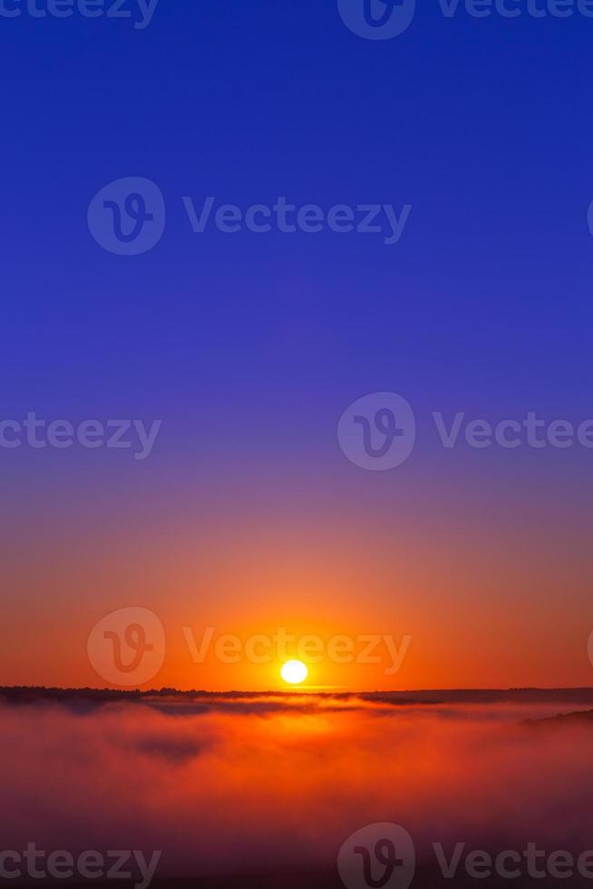 golden-blue summer sunrise over fog without clouds in minimalistic composition photo