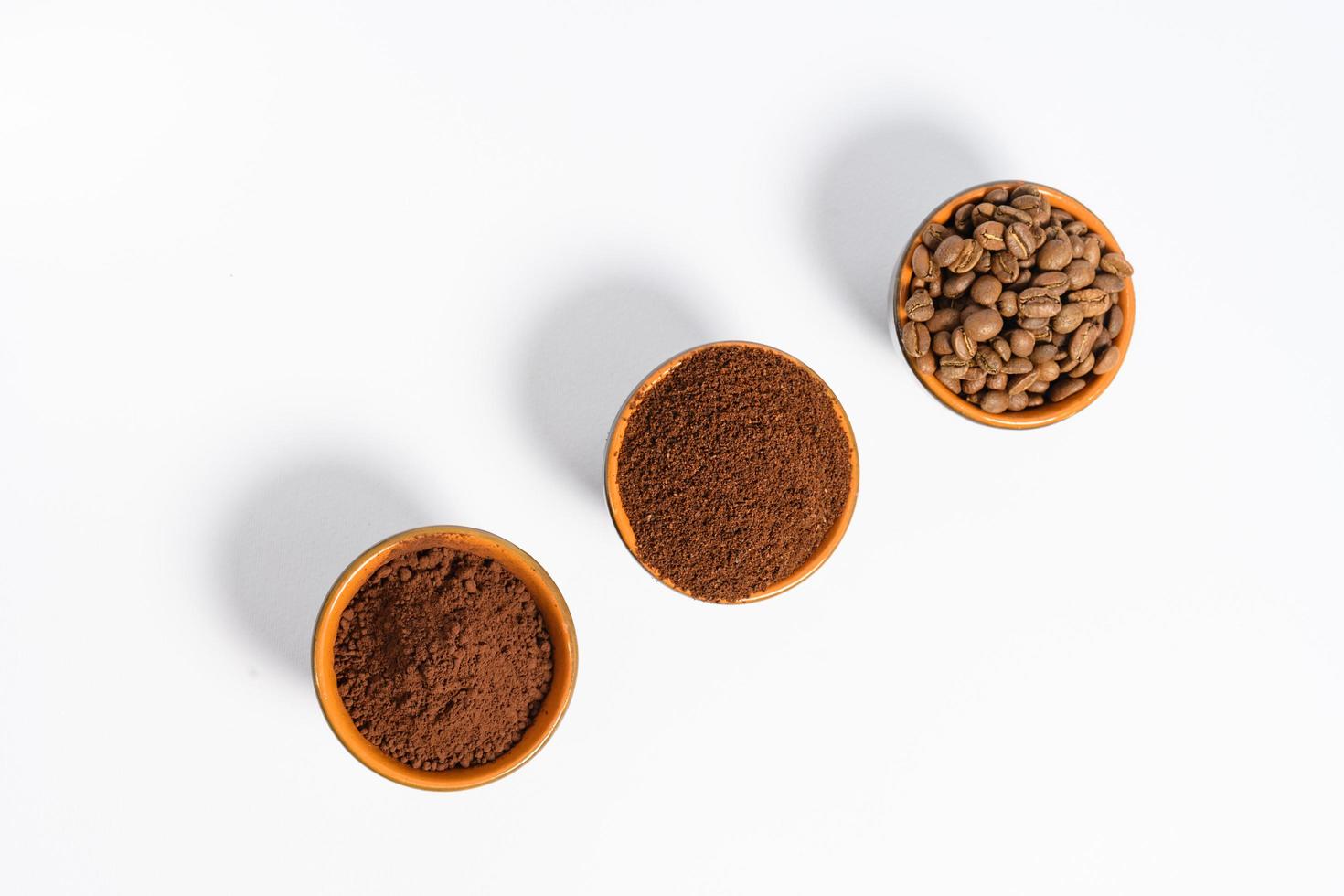 Three cups of coffee beans, ground coffee and cocoa for comparison. photo