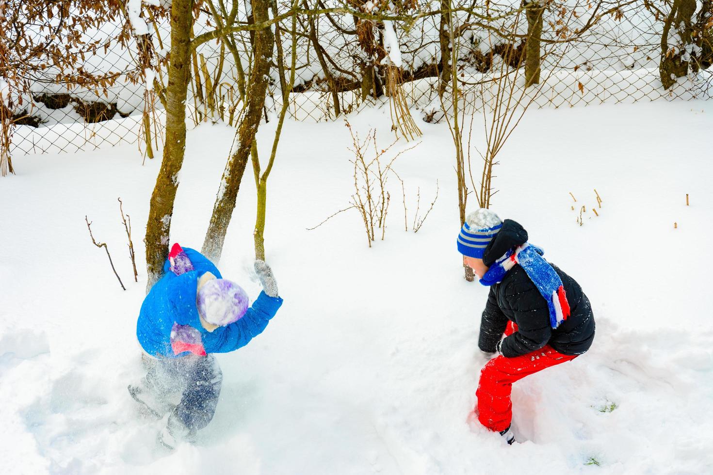 Two boys play snowballs, a fun game during the winter, a happy childhood for children. photo