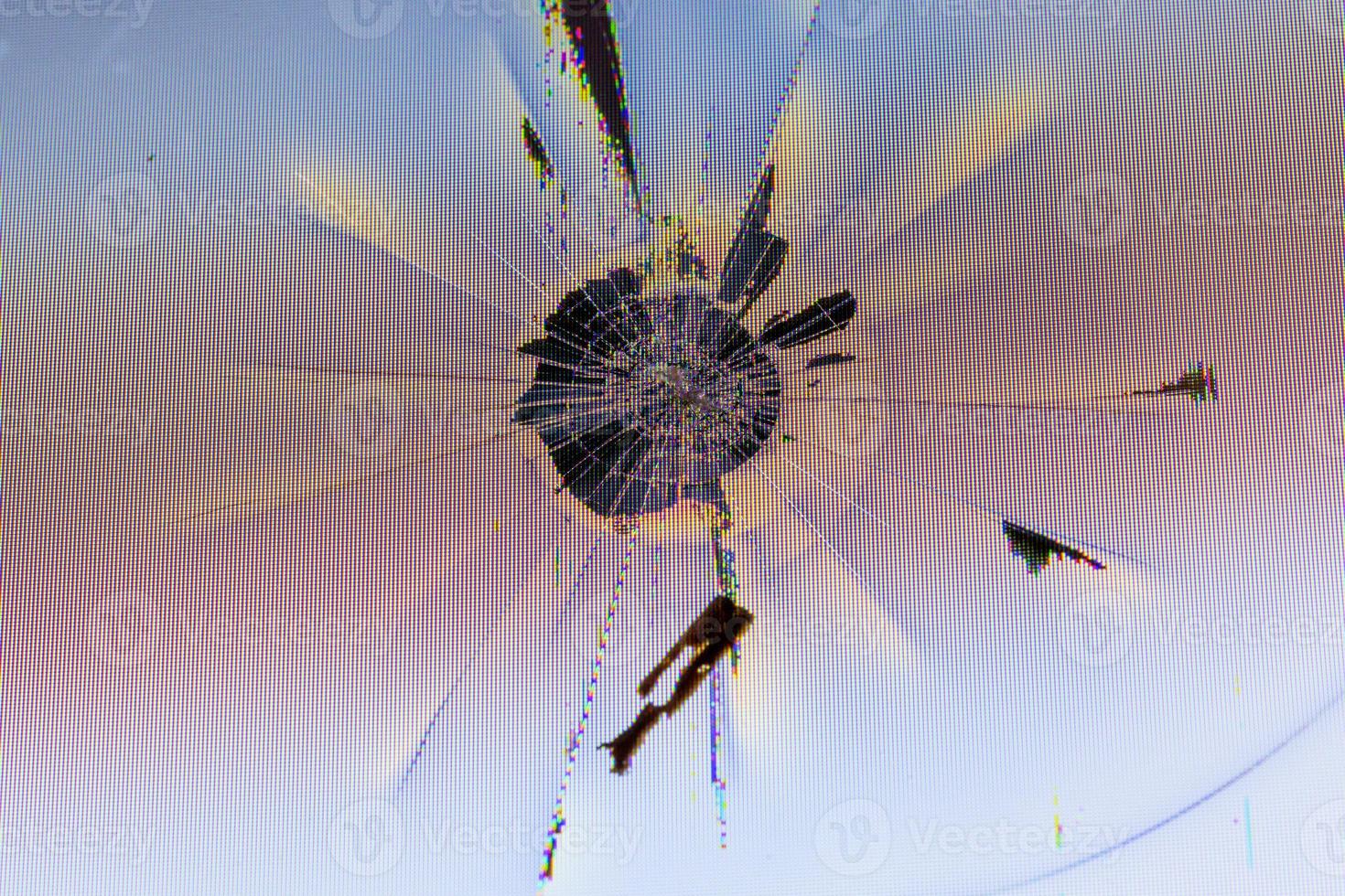 close-up view of physically damaged lcd screen surface with impact spot, radial cracks, pixel grid leakage and discoloration photo