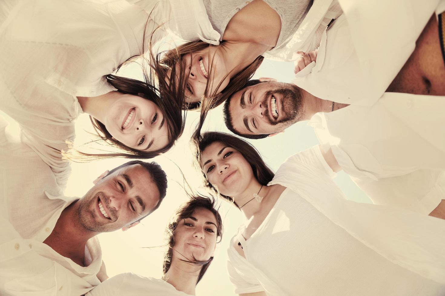 Group of happy young people in circle at beach photo