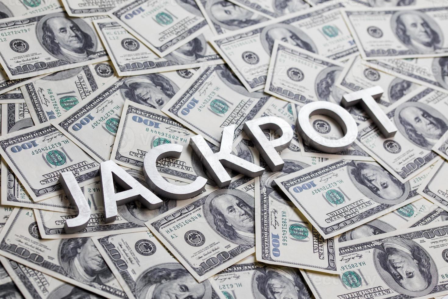 The word JACKPOT laid with aluminium letters on the US dollar banknotes background - with selective focus photo