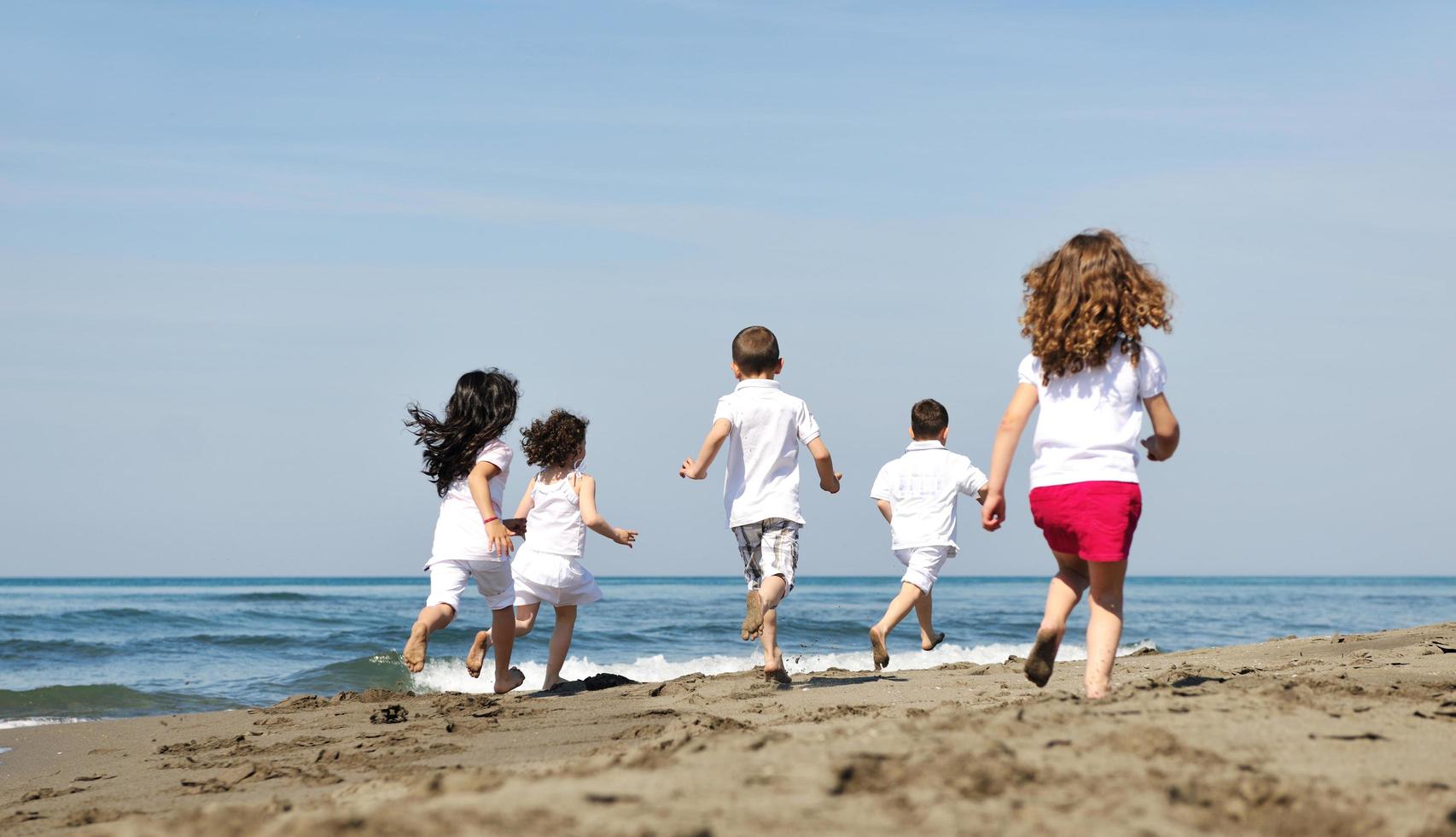 happy child group playing  on beach photo