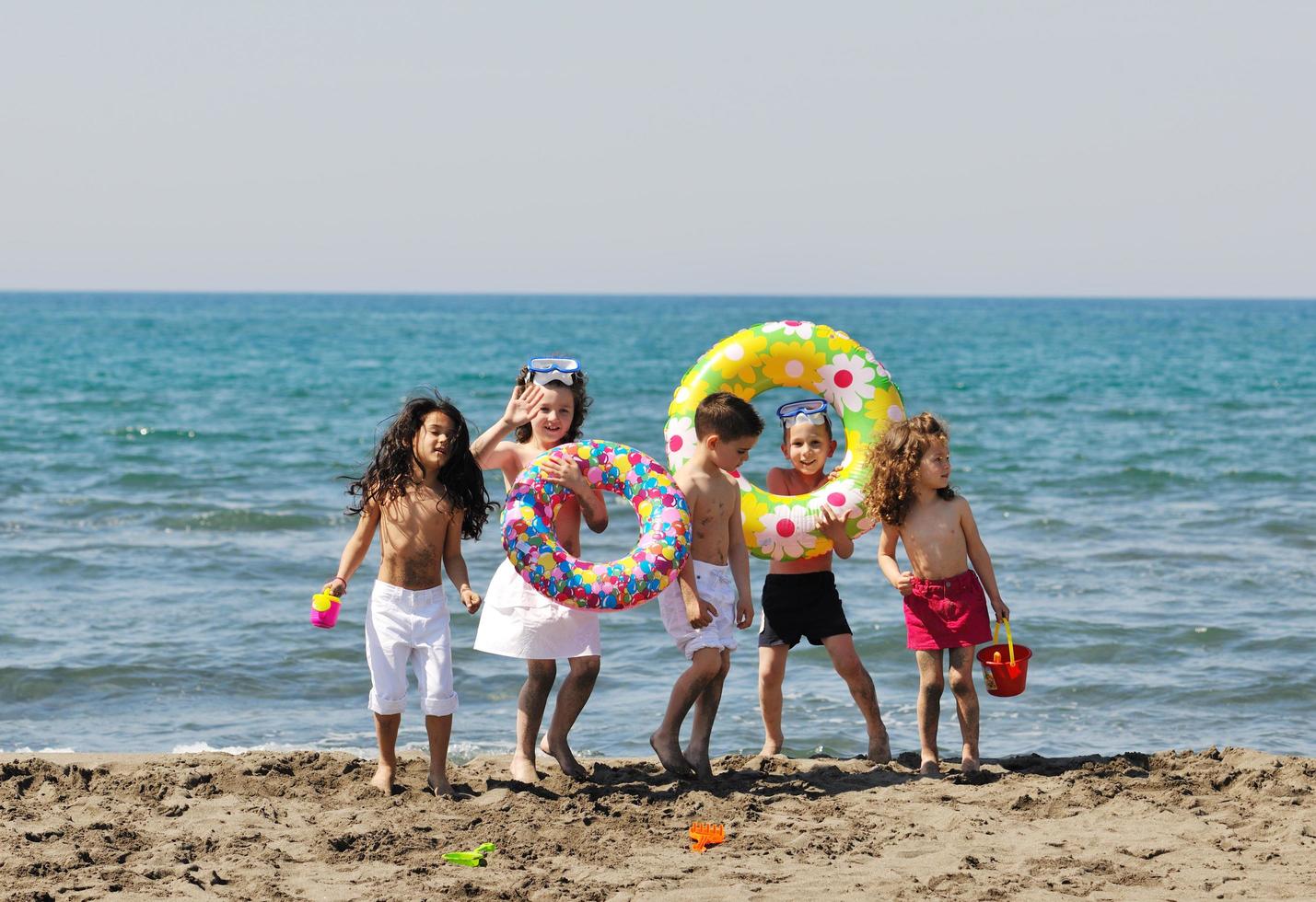 grupo infantil divertirse y jugar con juguetes de playa foto