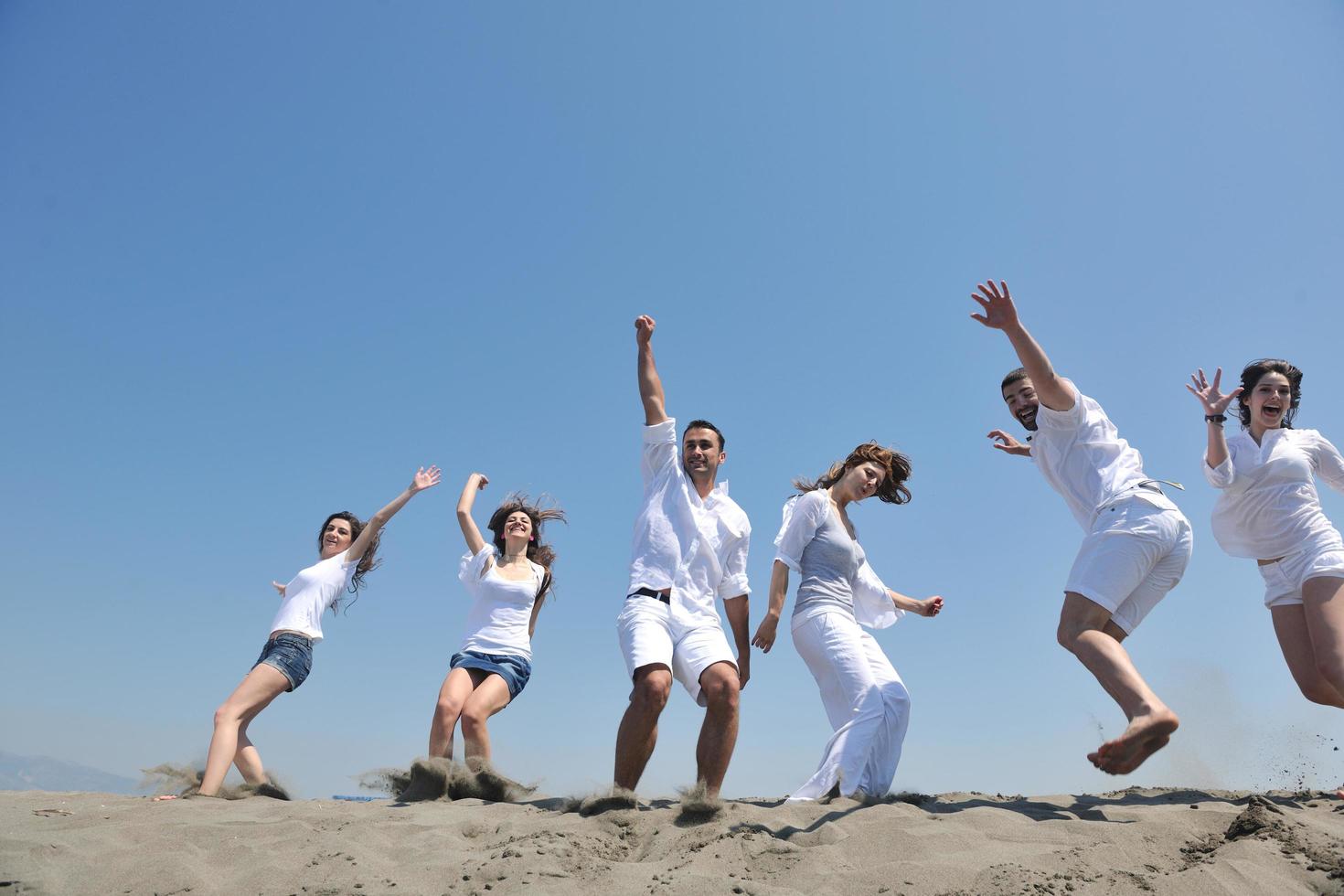 grupo de gente feliz divertirse y correr en la playa foto